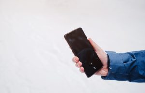 cell phone in a man's hand against a beautiful snowy winter forest background